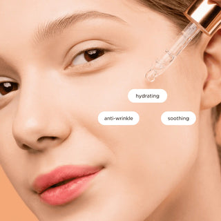 Close-up of a woman's face with a dropper applying skincare product, labeled for hydration, anti-wrinkle, and soothing.