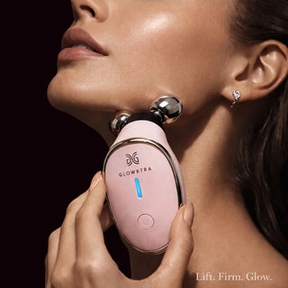Woman using GlowXtra pink microcurrent facial roller along the jawline