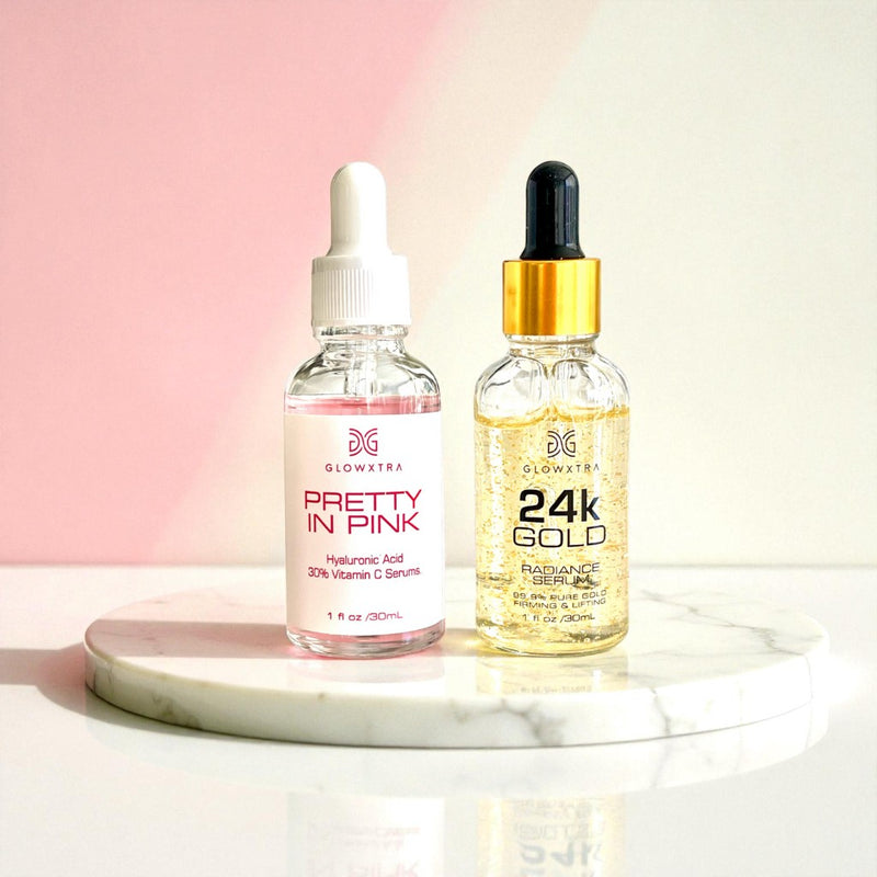 Two skincare serum bottles, one labeled 'Pretty in Pink' and the other '24K Gold', on a marble surface with a gradient background.