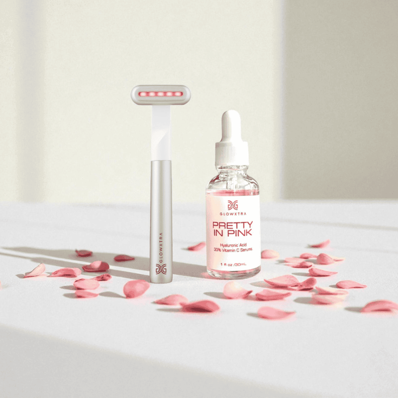 Skincare products with 'Pretty in Pink' label on a white surface with pink petals.