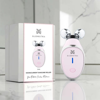 Pink skincare roller with packaging on a marble surface